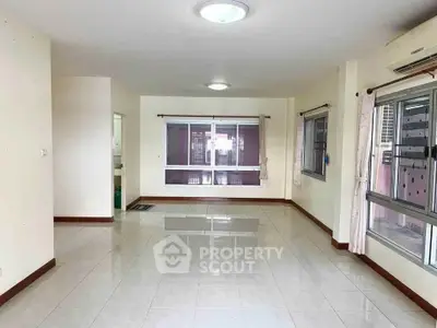 Spacious empty living room with large windows and tiled flooring