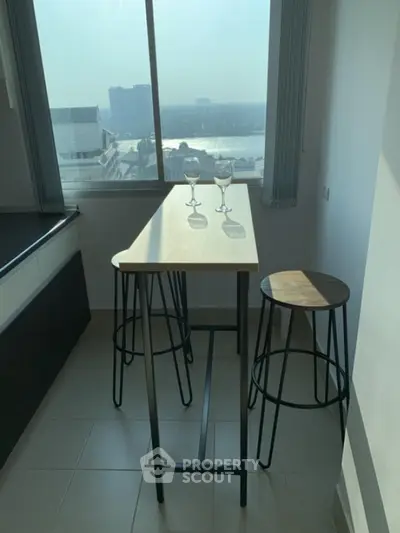Modern kitchen nook with high table and stools offering stunning city view.