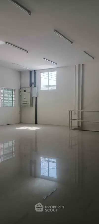 Spacious and bright empty room with glossy floors and large windows, ideal for customization.