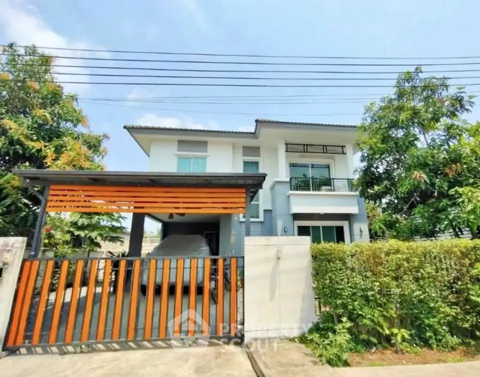 Modern two-story house with carport and lush greenery in a serene neighborhood.