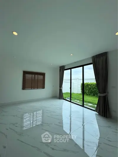 Spacious modern living room with large windows and garden view, perfect for natural light lovers.