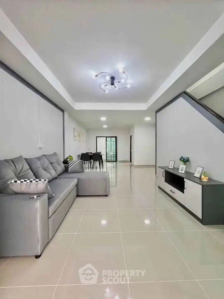 Spacious modern living room with sleek gray sofa and elegant lighting, perfect for family gatherings.