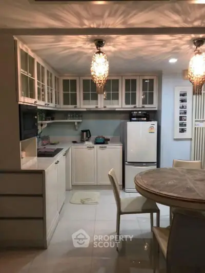 Charming kitchen with elegant lighting, modern appliances, and cozy dining area in a stylish home.