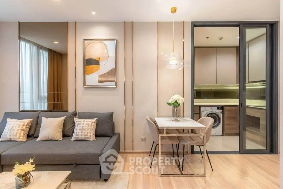Modern living room with stylish decor and adjacent kitchen featuring sleek appliances.