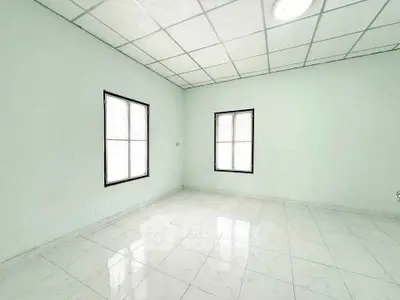 Spacious empty room with tiled floor and two windows, ideal for customization.