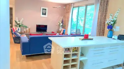 Spacious living room with modern decor and large windows opening to a lush green view.