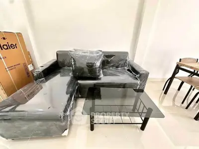 Modern living room with sleek black sofa and glass coffee table, perfect for contemporary interiors.