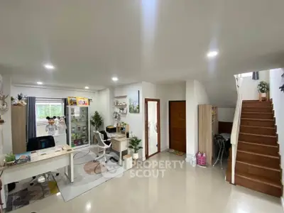 Spacious modern living room with study area and staircase, featuring sleek furniture and bright lighting.