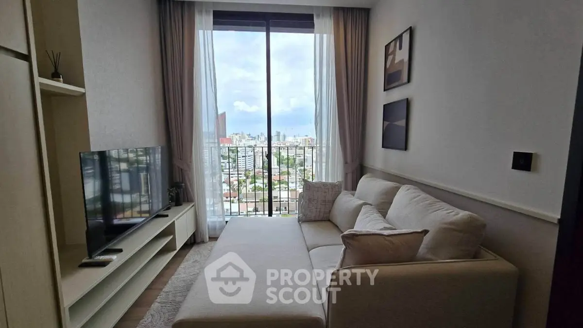 Modern living room with large window offering stunning city view, cozy sofa, and sleek TV setup.