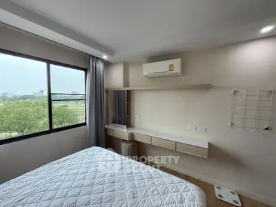 Modern bedroom with large window and air conditioning, offering a serene view of greenery.