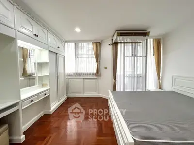 Spacious bedroom with elegant wooden flooring and ample natural light