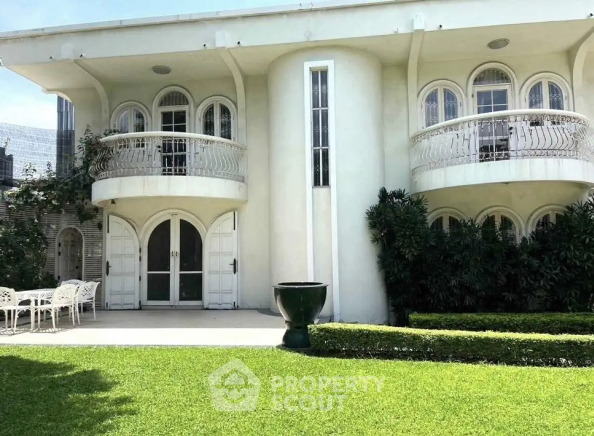 Elegant two-story building with arched windows and lush garden, perfect for luxury living.