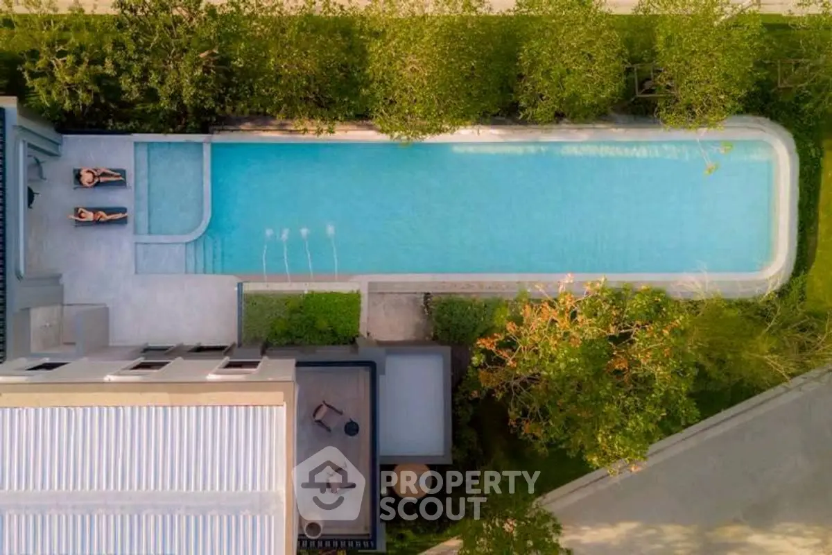 Luxurious aerial view of modern property with stunning pool and lush greenery.