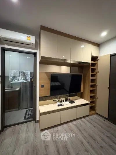 Modern living room with sleek cabinetry and wall-mounted TV, featuring stylish wood flooring and contemporary design.