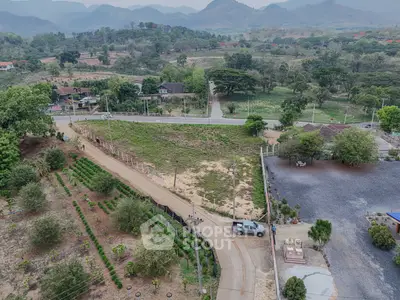 Scenic aerial view of lush landscape with winding road and distant mountains, ideal for real estate development.