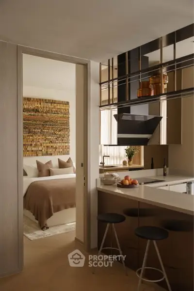 Modern kitchen with breakfast bar leading to cozy bedroom with stylish decor.
