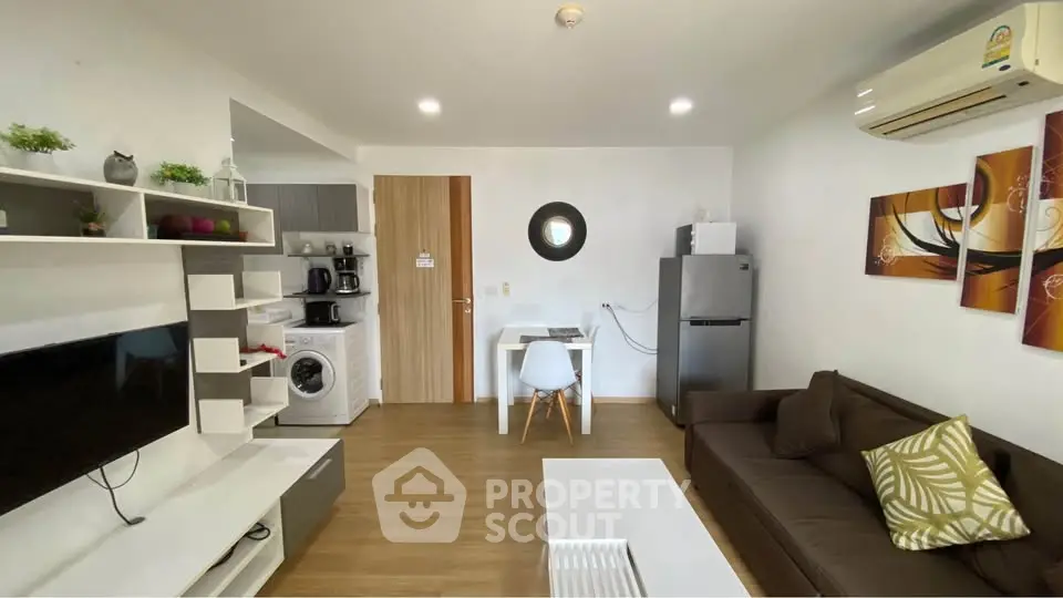 Modern living room with open kitchen, featuring sleek furniture and appliances, ideal for urban living.