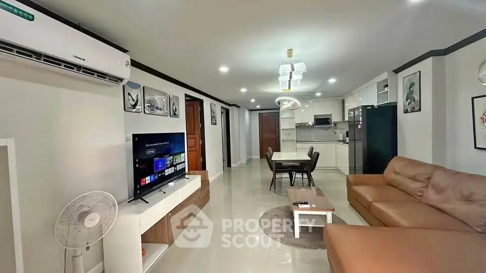 Spacious modern living room with open kitchen, featuring sleek furniture and contemporary decor.