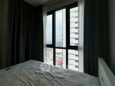 Cozy bedroom with city view through large windows and elegant curtains.