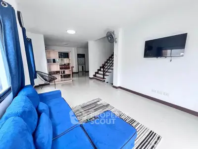 Spacious living room with blue sofa and wall-mounted TV in modern home