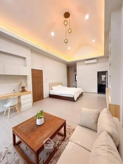 Spacious modern bedroom with elegant lighting and cozy seating area.