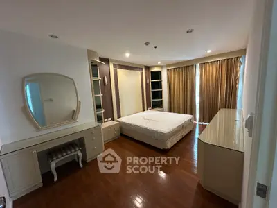 Spacious bedroom with elegant wooden flooring and ample natural light