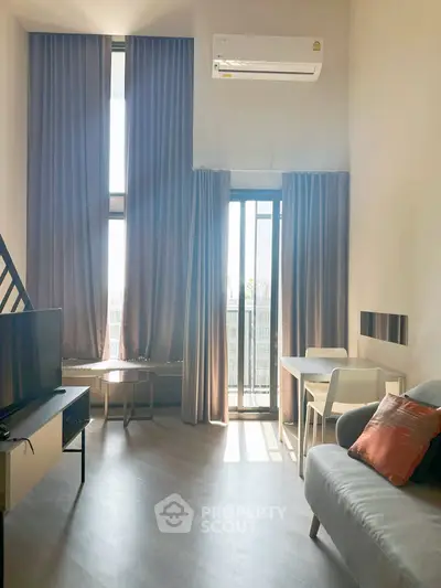 Modern living room with high ceilings, large windows, and stylish furniture in a bright apartment.