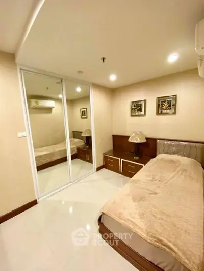 Cozy bedroom with mirrored closet and modern decor in a stylish apartment.