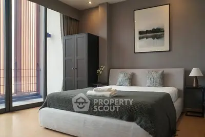 Modern bedroom with large window and stylish decor in urban apartment.