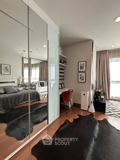 Stylish bedroom with mirrored wardrobe and cozy study nook, featuring modern decor and ample natural light.
