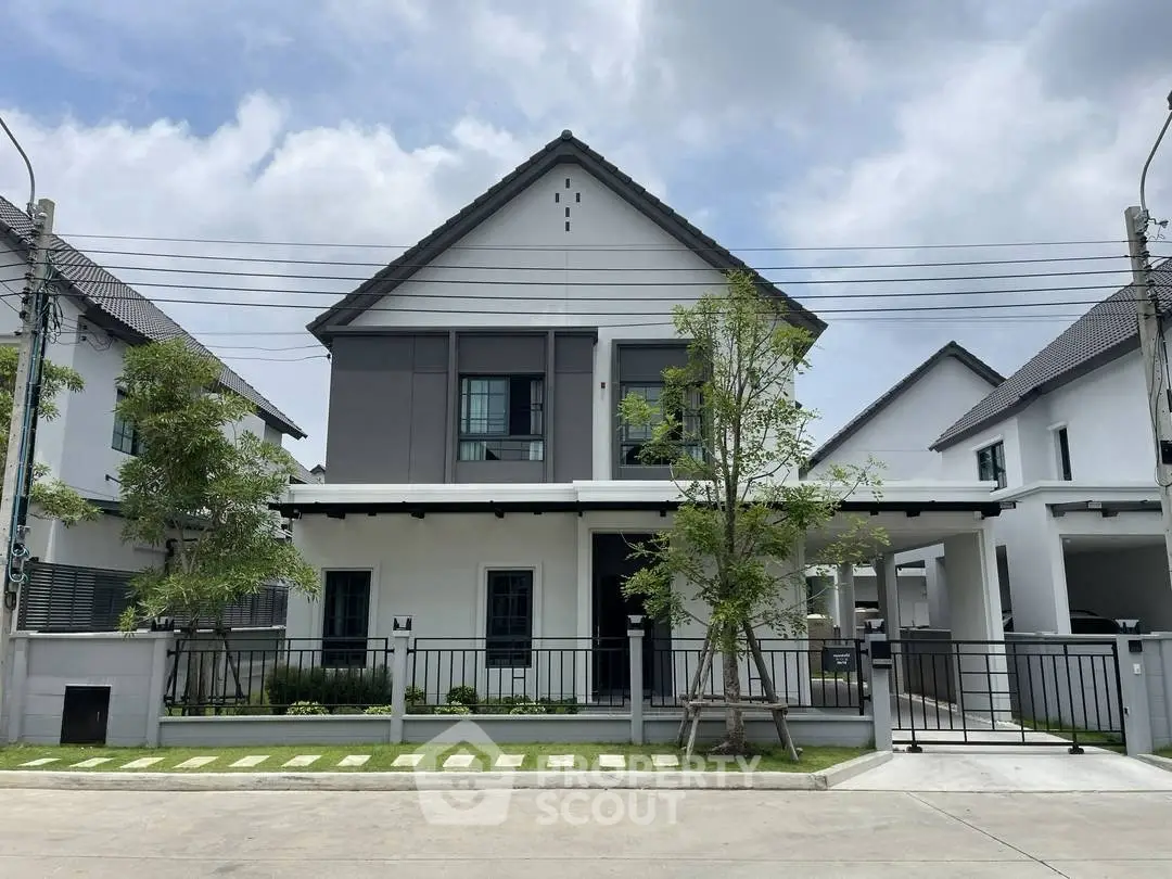 Modern two-story house with sleek design and spacious driveway in a suburban neighborhood.