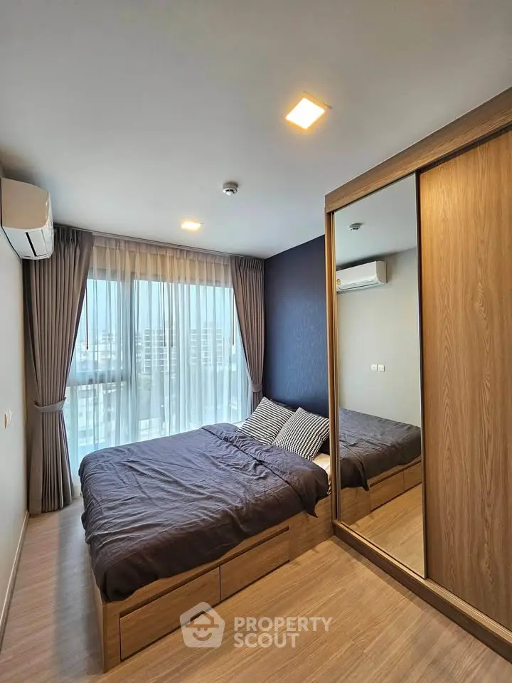 Modern bedroom with large window and mirrored wardrobe in stylish apartment