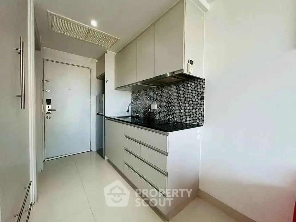 Modern kitchen with sleek cabinetry and stylish backsplash in a compact layout.