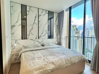 Luxurious bedroom with floor-to-ceiling windows offering stunning city views and elegant marble accents.
