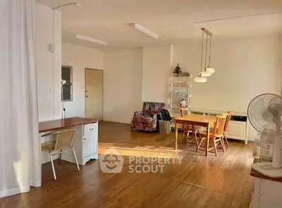 Spacious living room with wooden flooring, dining area, and cozy seating in a bright, open layout.