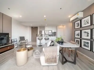Modern open-plan living room with stylish decor and kitchen area, featuring contemporary furniture and wall art.