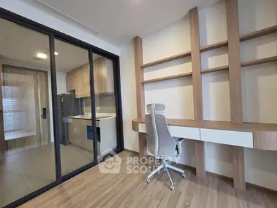 Modern study room with built-in desk and shelves, adjacent to sleek kitchen.