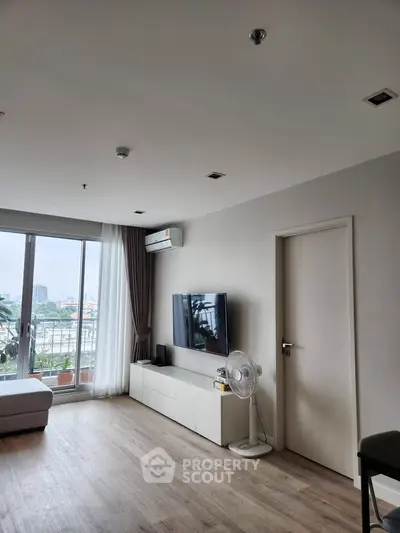 Modern living room with large windows and city view, featuring sleek furniture and minimalist decor.