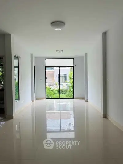 Spacious empty living room with large windows and glossy tiled floor