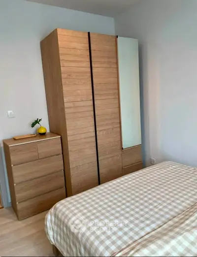 Cozy bedroom with wooden wardrobe and checkered bedding, perfect for a minimalist lifestyle.