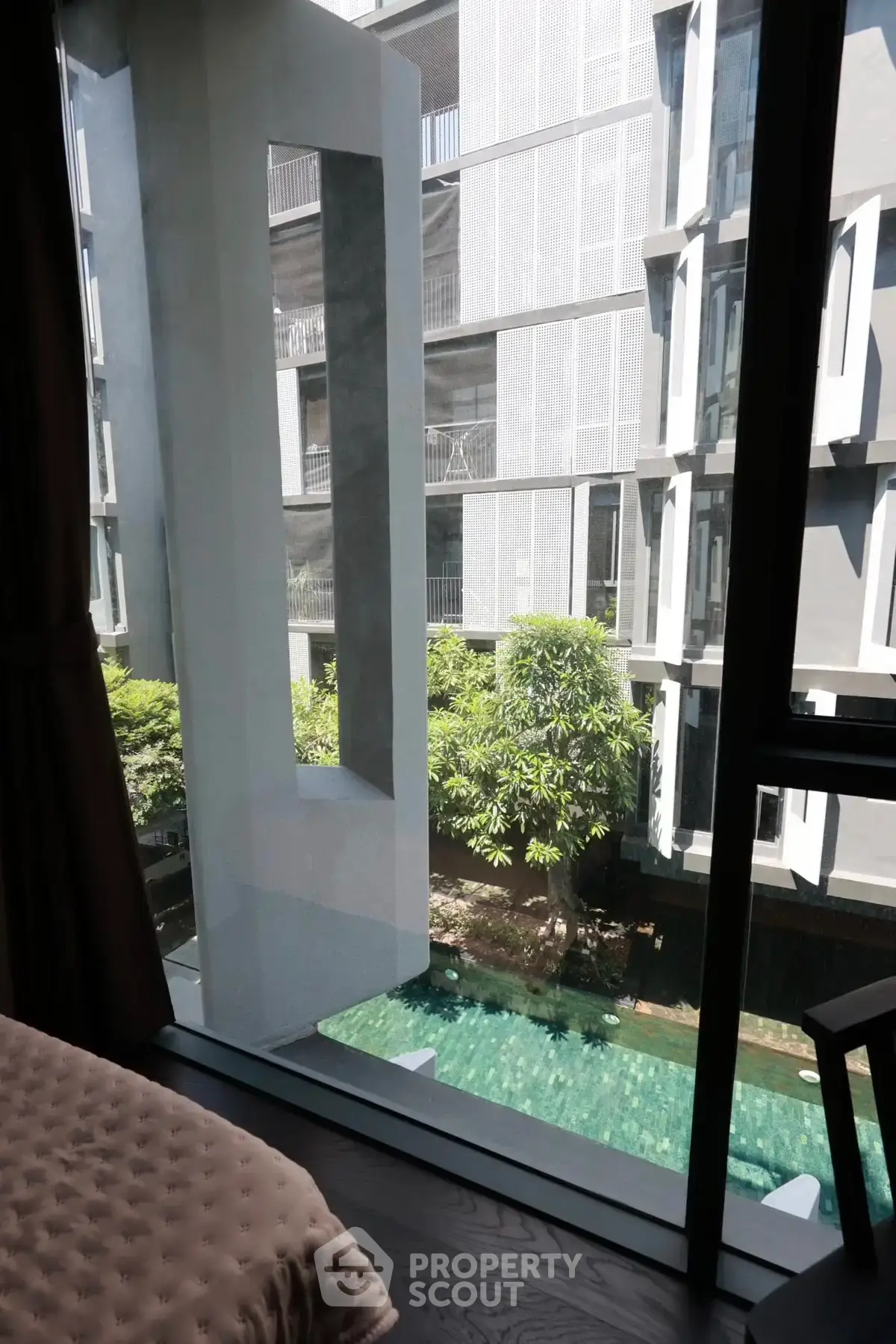 Modern apartment view with pool and lush greenery, offering serene urban living.