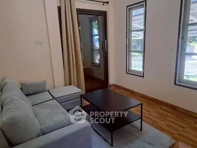 Cozy living room with modern sofa and coffee table, featuring large windows and natural light.