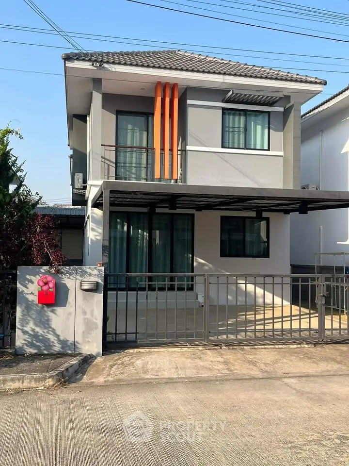 Modern two-story house with stylish facade and gated entrance in a suburban neighborhood.
