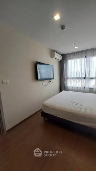 Modern bedroom with wall-mounted TV and large window view.