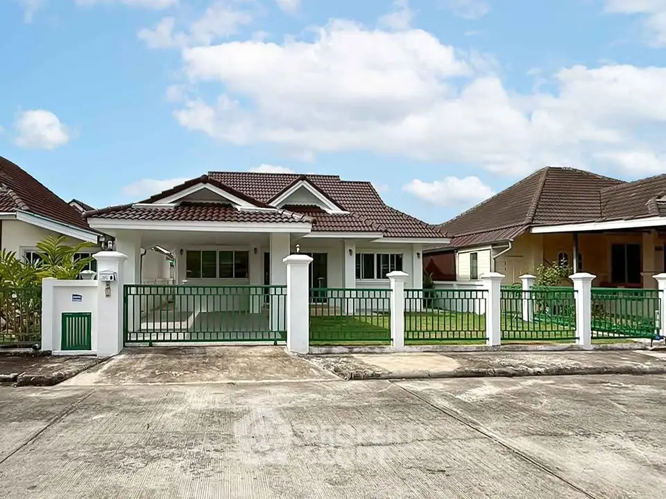 Charming single-story house with tiled roof and fenced front yard in a serene neighborhood.