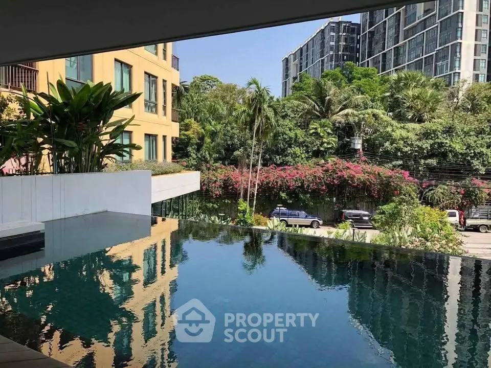 Luxurious infinity pool with lush greenery and modern buildings in the background, perfect for relaxation.