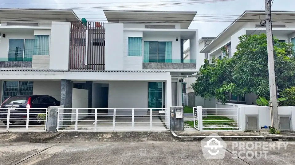 Modern two-story house with sleek design, large windows, and a spacious driveway in a suburban neighborhood.