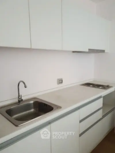 Modern minimalist kitchen with sleek white cabinetry and stainless steel sink