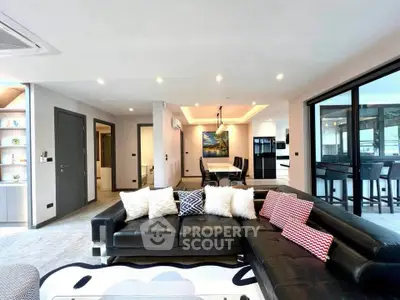 Luxurious modern living room with sleek black leather sofa and open dining area