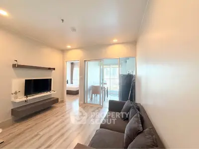 Modern living room with sleek design and open layout, featuring a wall-mounted TV and cozy seating area.